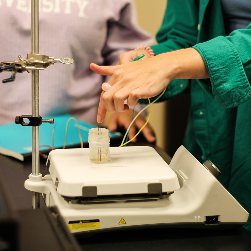 Close up of students hands working on a project in a lab