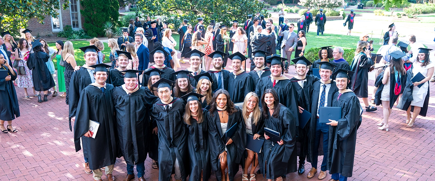 A group of students in their regalia posting after graduation