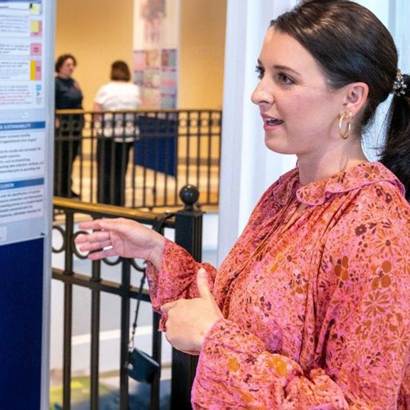 a Student presenting information on a poster at a SPARK event.