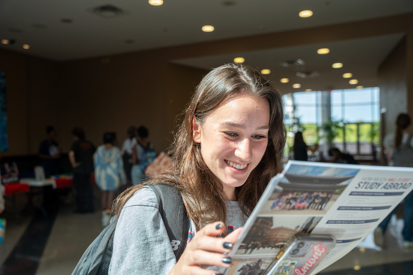 Student smiles while looking at a brochure