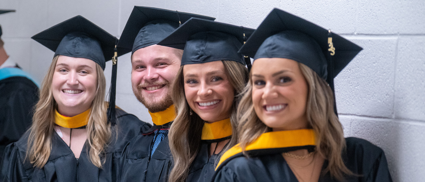 Four student pose before graduation in cap and gown. in 