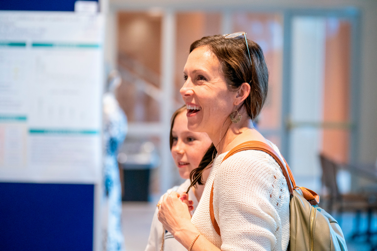 A woman listening to a student presentation and smiling