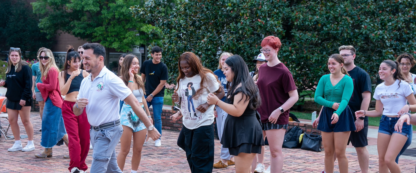 Students outdoors learning to salsa with an instructor 