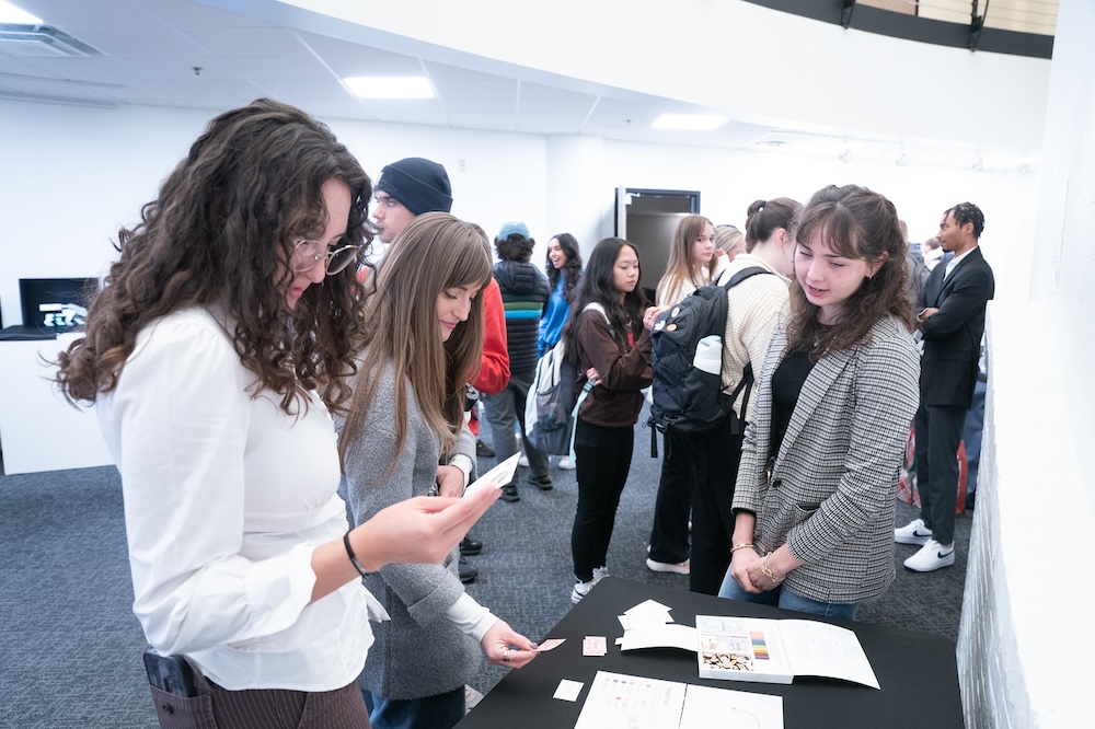 students look at another student's project at gallery opening