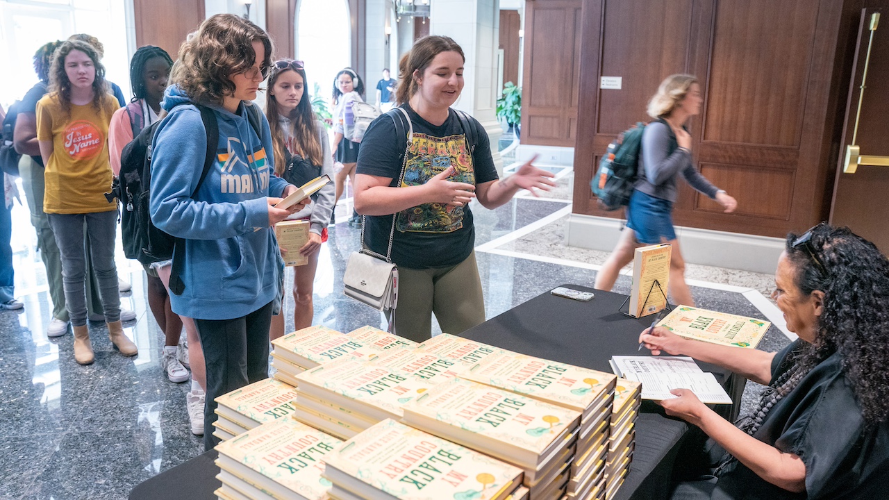 Randall speaking with students and signing copies of her book