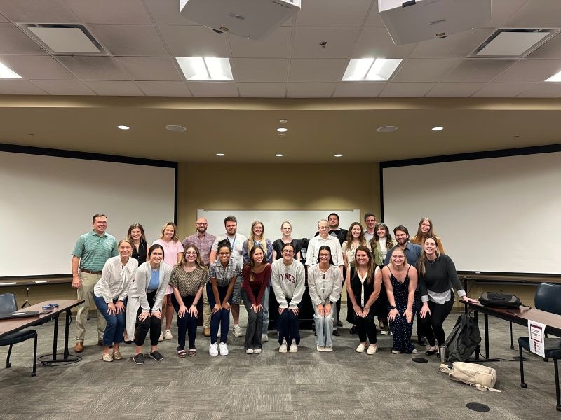 law school students smiling in front of a classroom