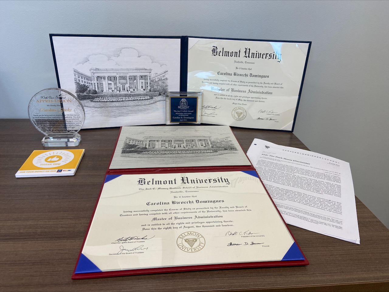 Carolina Guske's desk showing her Belmont diploma and graduate school case student about ALDI