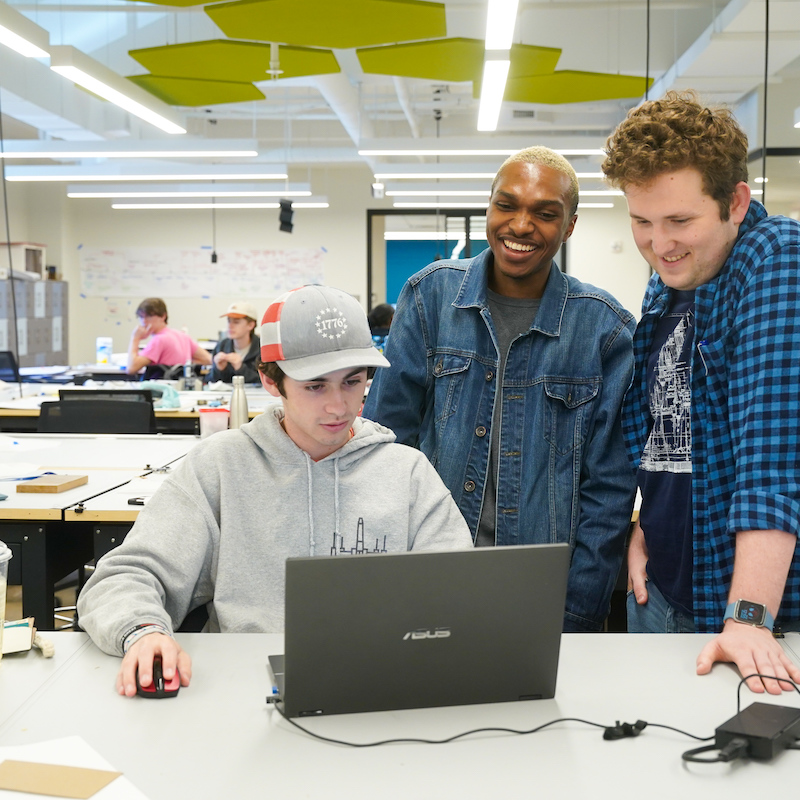 Three students around a laptop during an interior design class