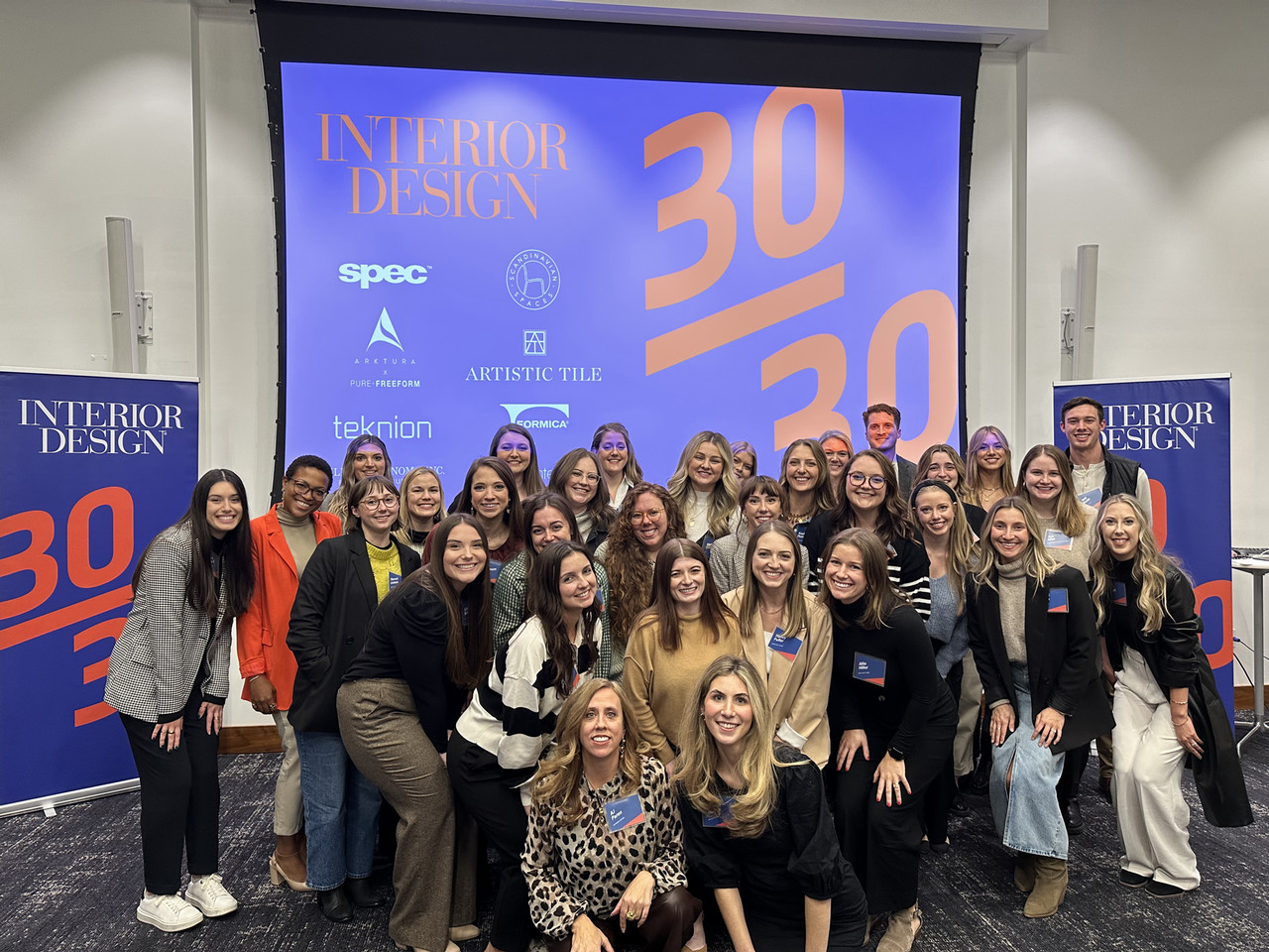 Group photo of the 30/30 participants in front of a screen with the logo on it