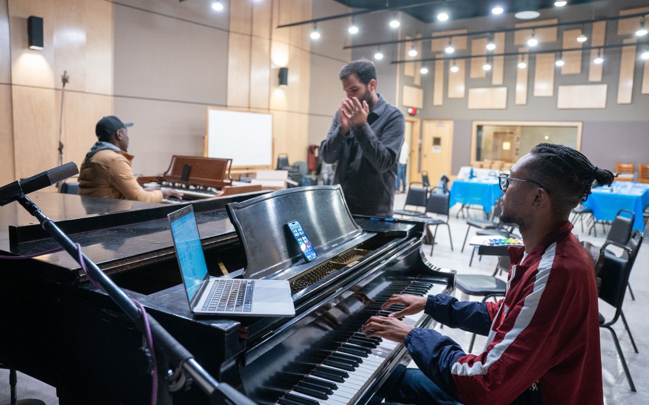 Group practices a song around a piano