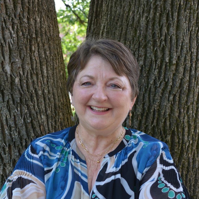 Annette Sisson poses in front of a tree