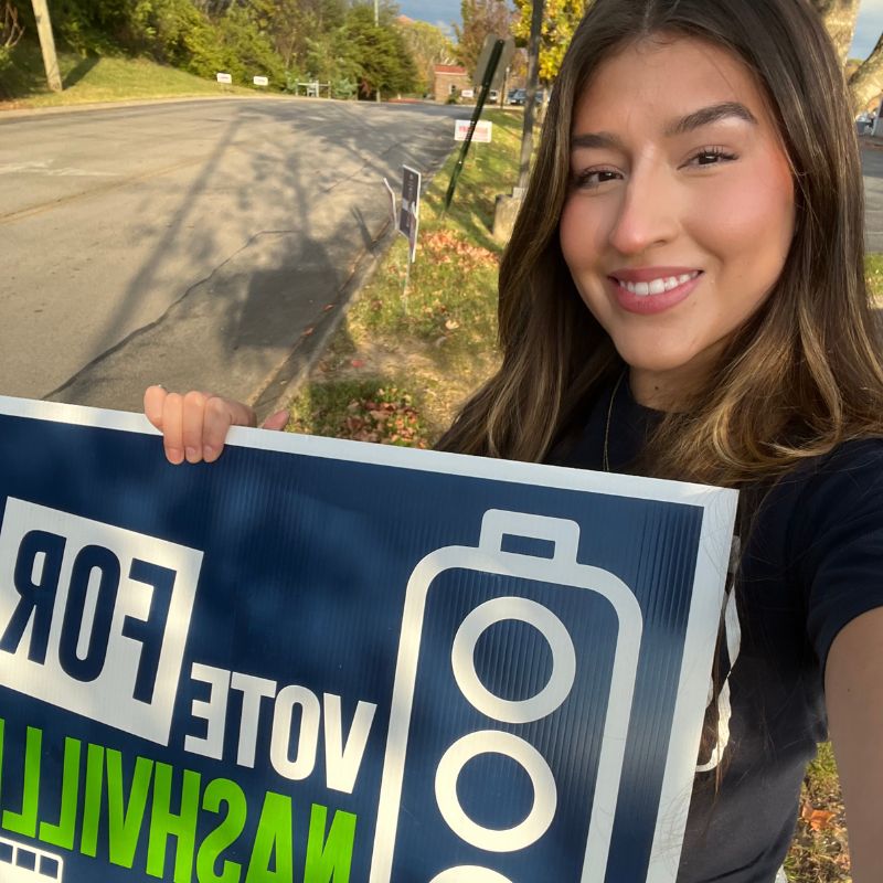 Paloma Buck holding a "Choose How You Move" transit sign