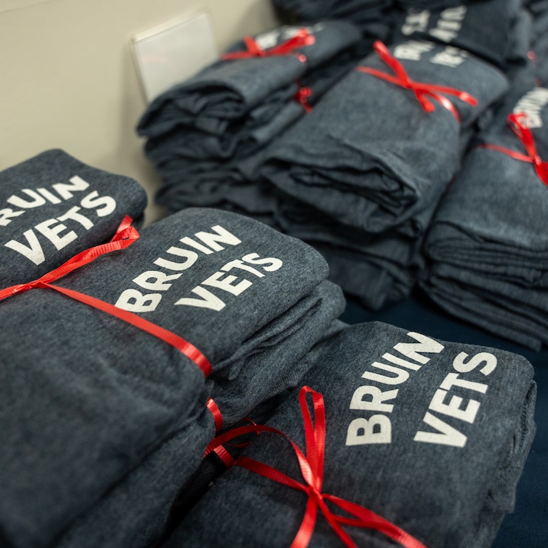 veterans week 2024 shirts stacked with a red ribbon on a table