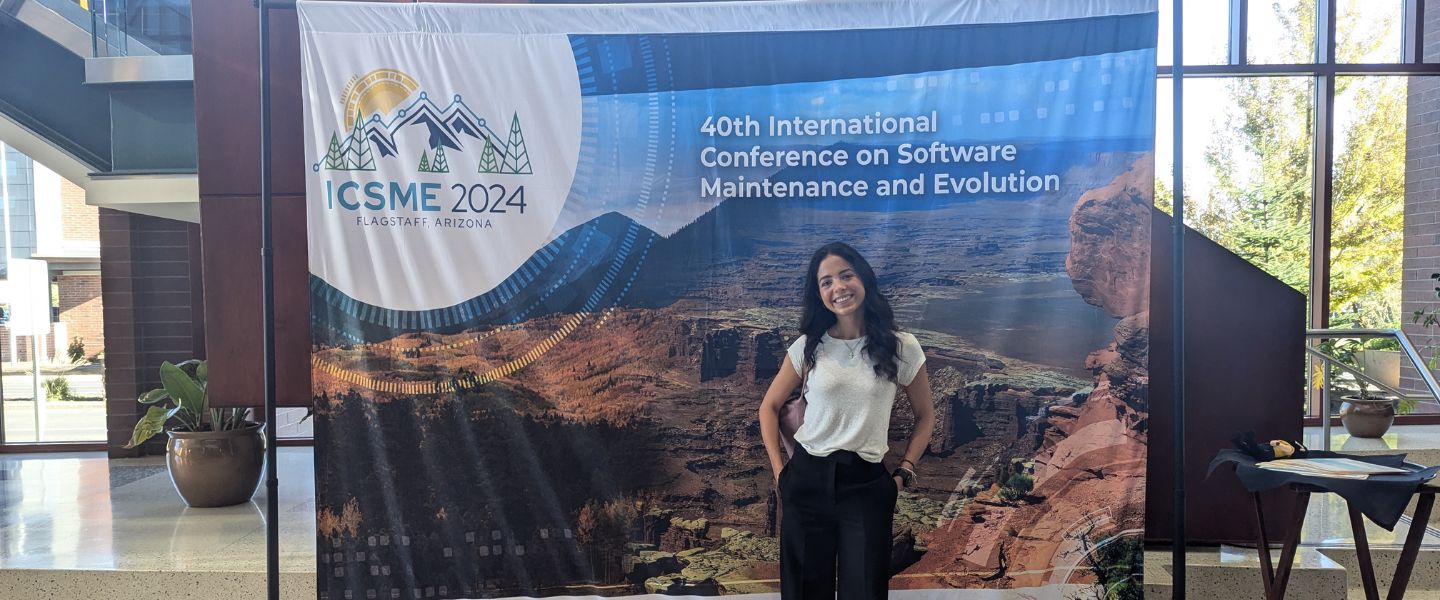 Blaire Lepore poses in front of a banner reading "ICSME 2024"