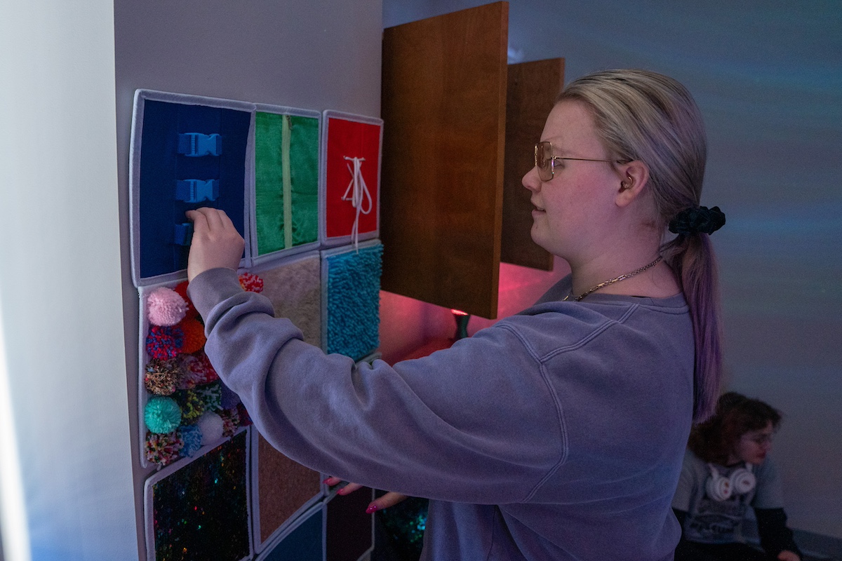 student using tactile wall features in Belmont's sensory room