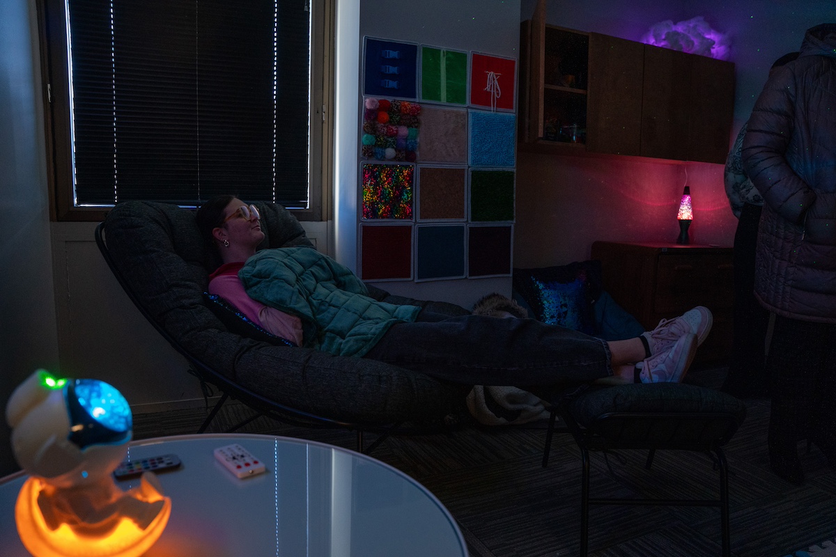 student sitting in a reclining chair with a weighted blanket in the sensory room