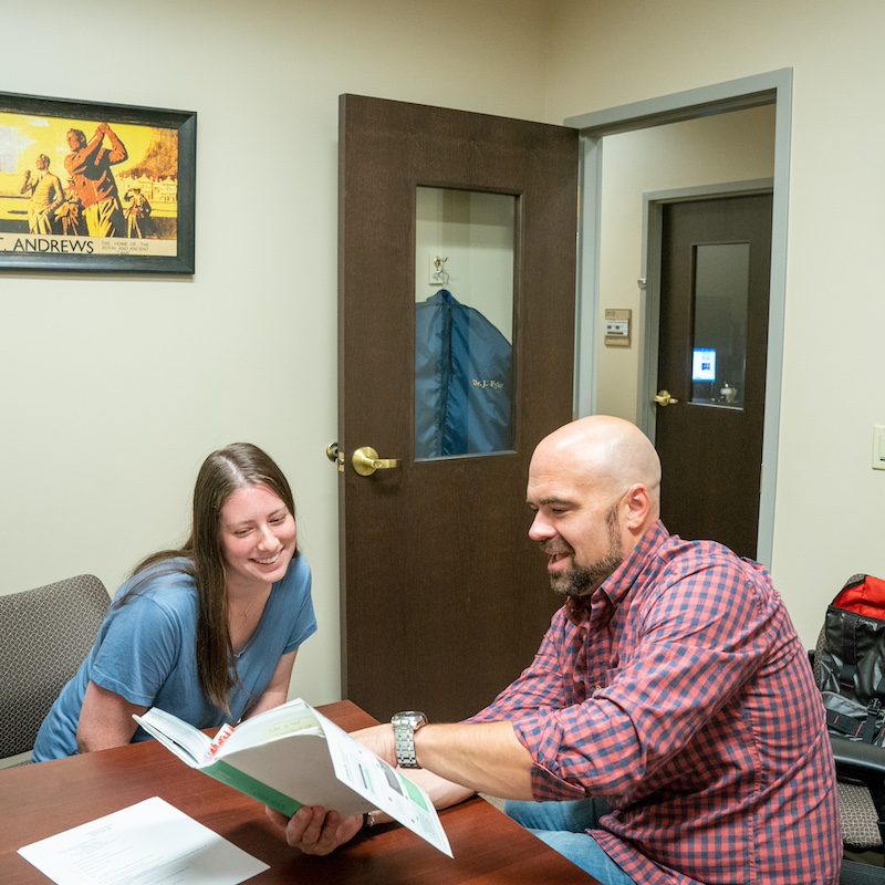 student and professor looking at a book together