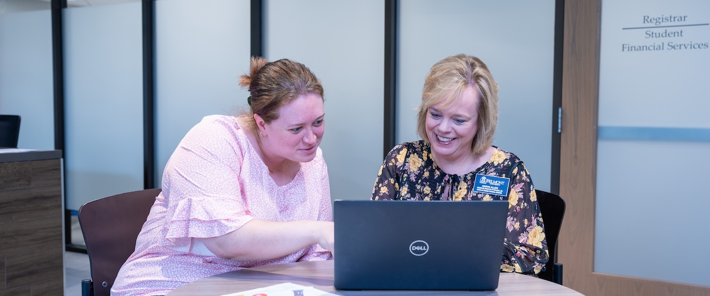 a student and a Belmont employee work together on a laptop