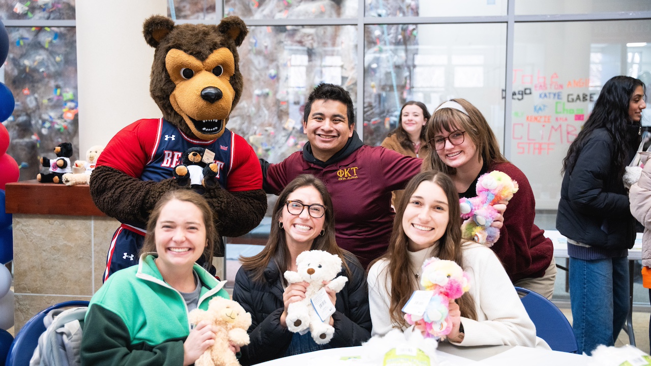 students and Bruiser the Bruins holding up stuffed bruins