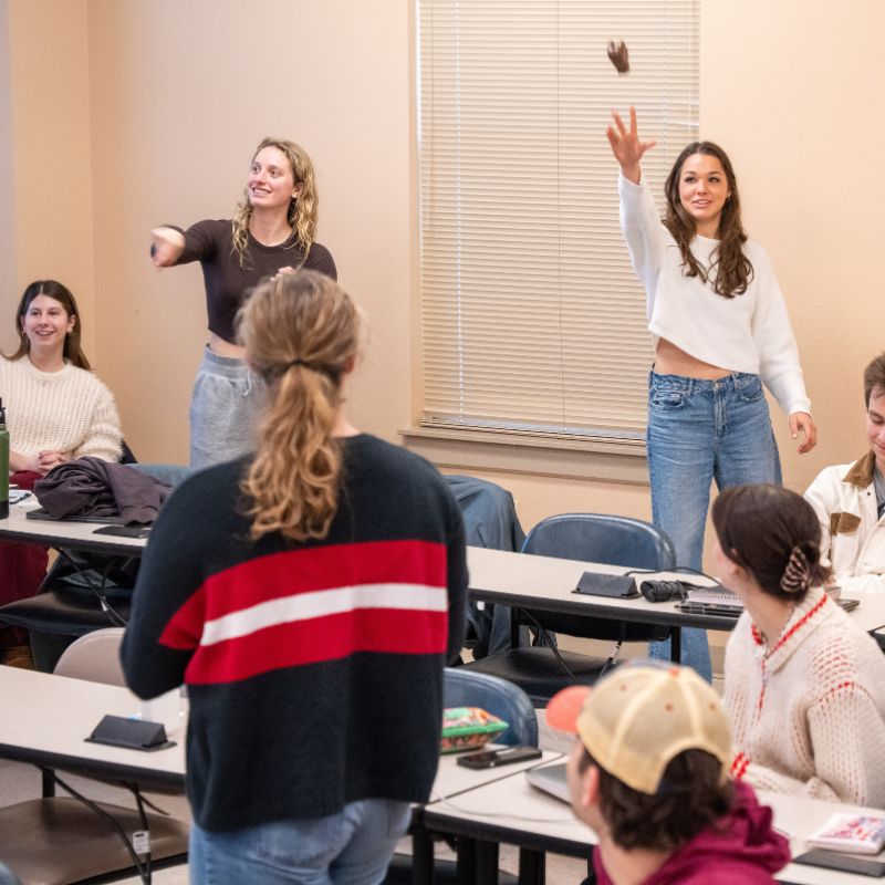 Students throw an object around the classroom