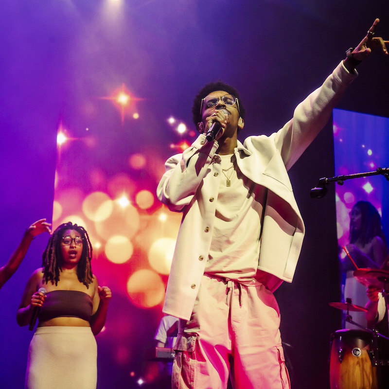 singer in a suit and backup singer under purple lighting