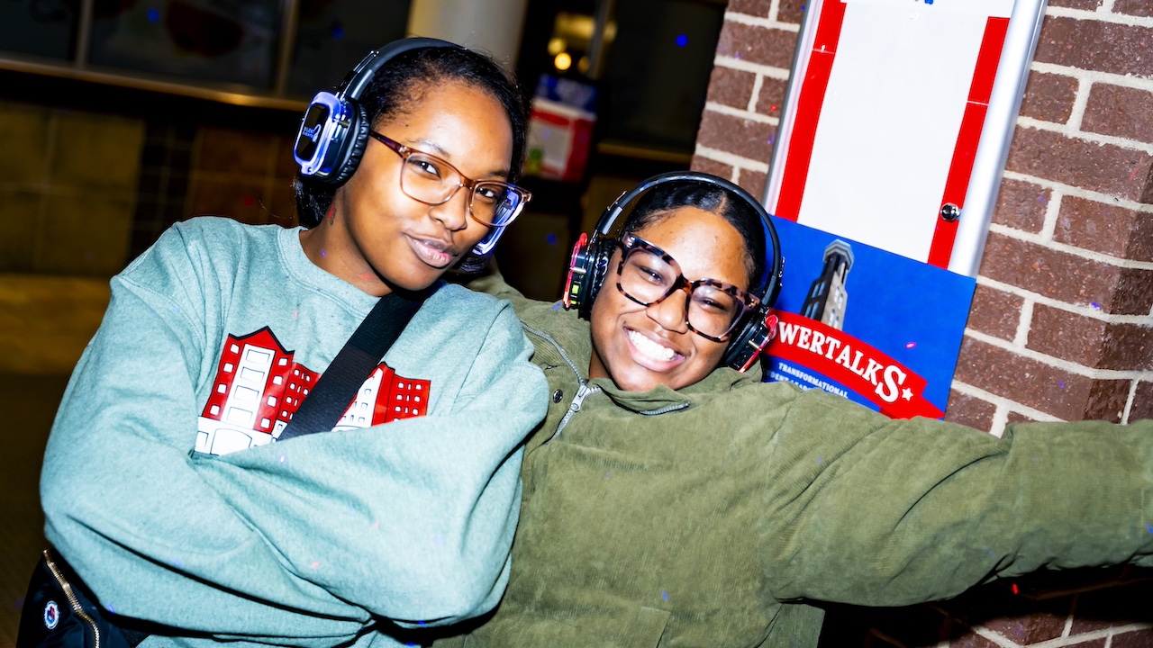 two smiling students with silent disco headphones