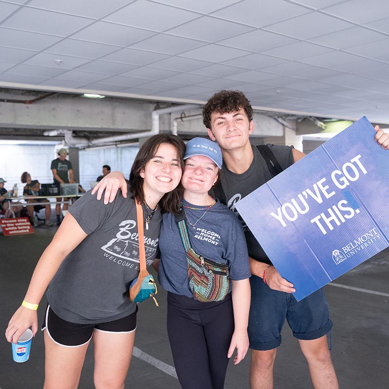 3 students smiling for the camera while holding up a blue sign that says "You Got This"