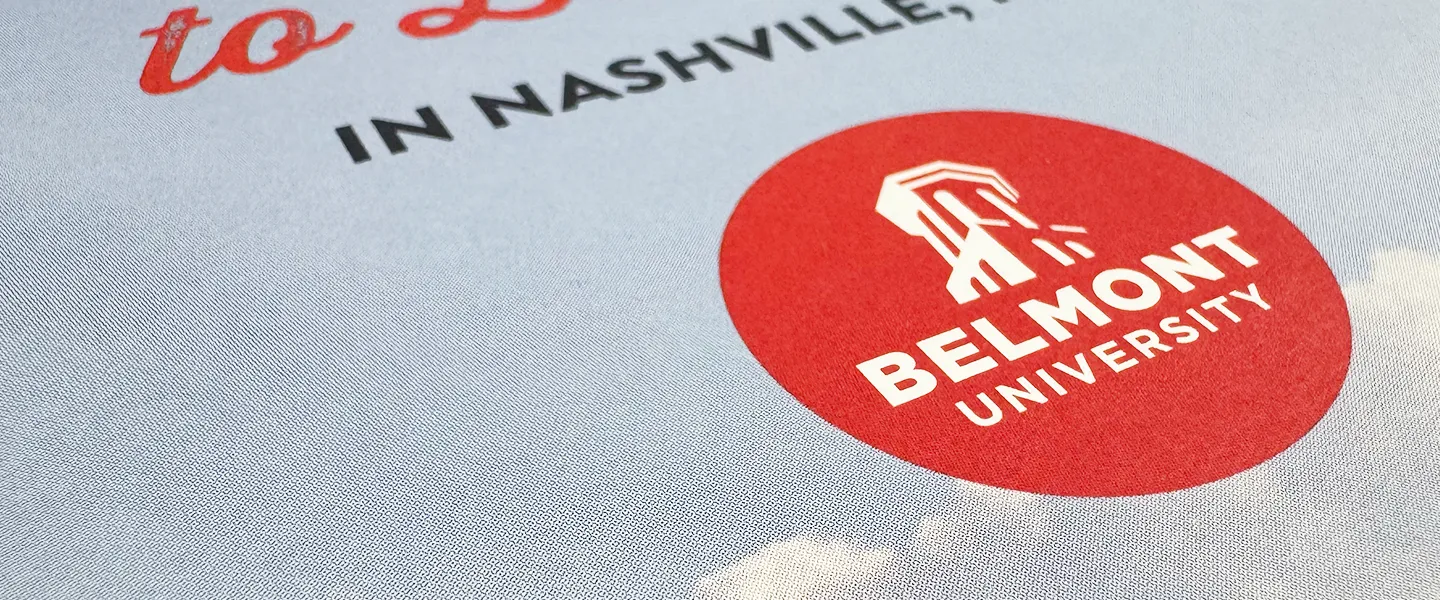 Close-up of a Belmont University logo printed on a textured surface, featuring a red circle with the university's name and an emblem inside.