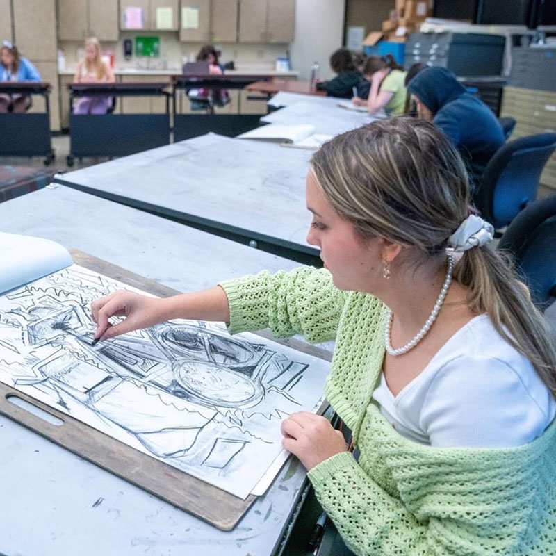 A student draws a still life from observation in the studio space.