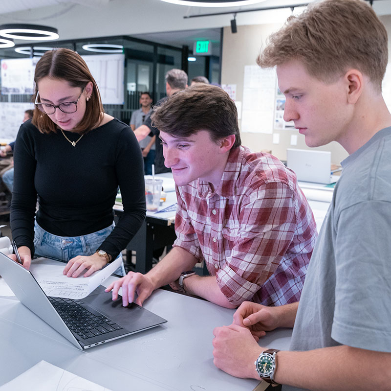 Three students converse over the computer about course findings.