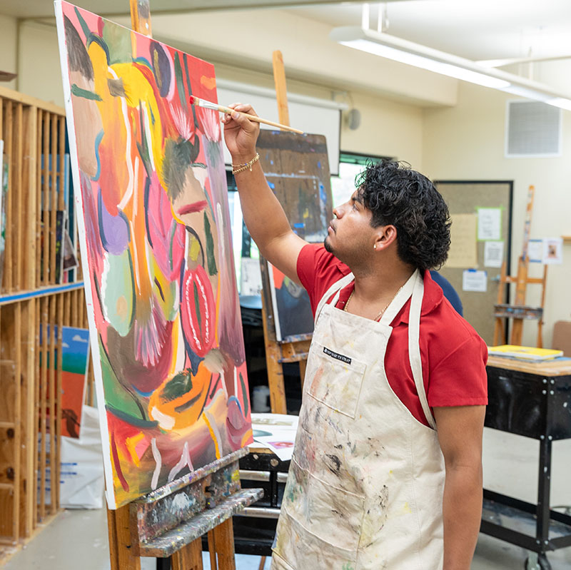 image of student painting at an easel