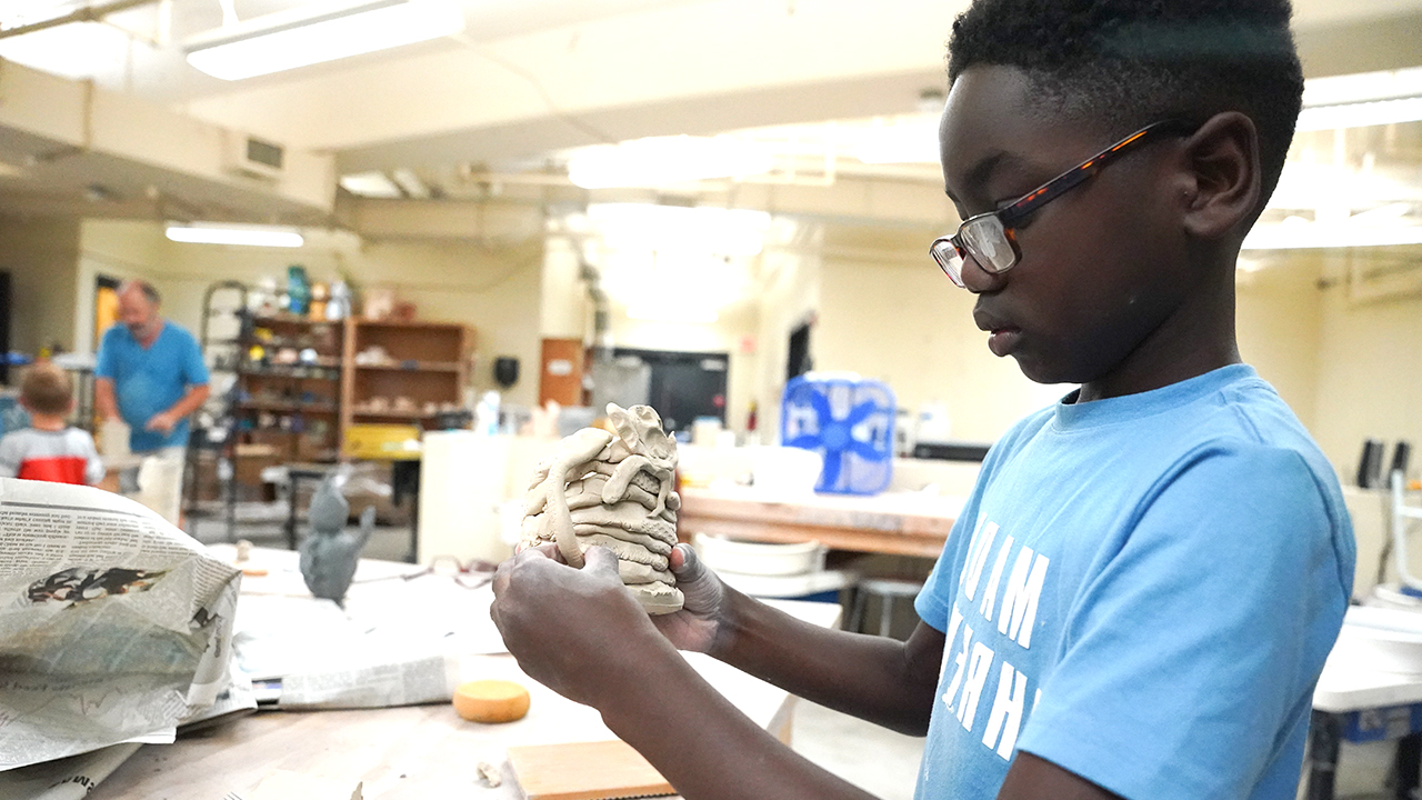 Kid creating a cup with clay