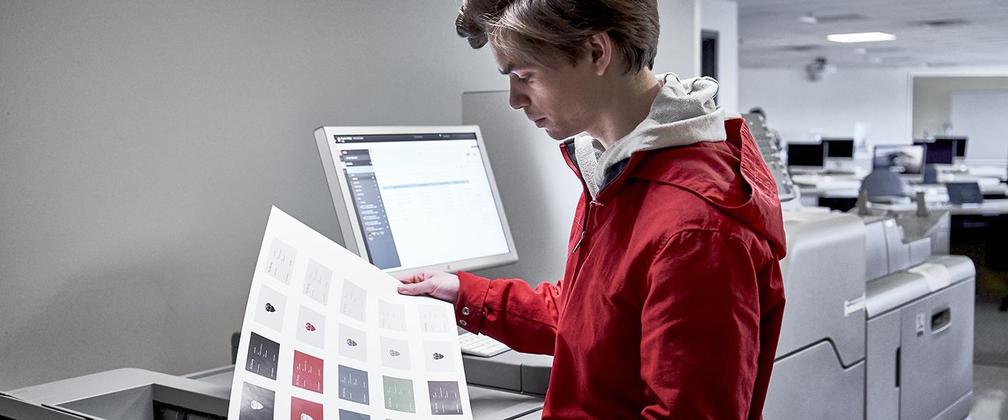 Student looking at printed out designs in classroom