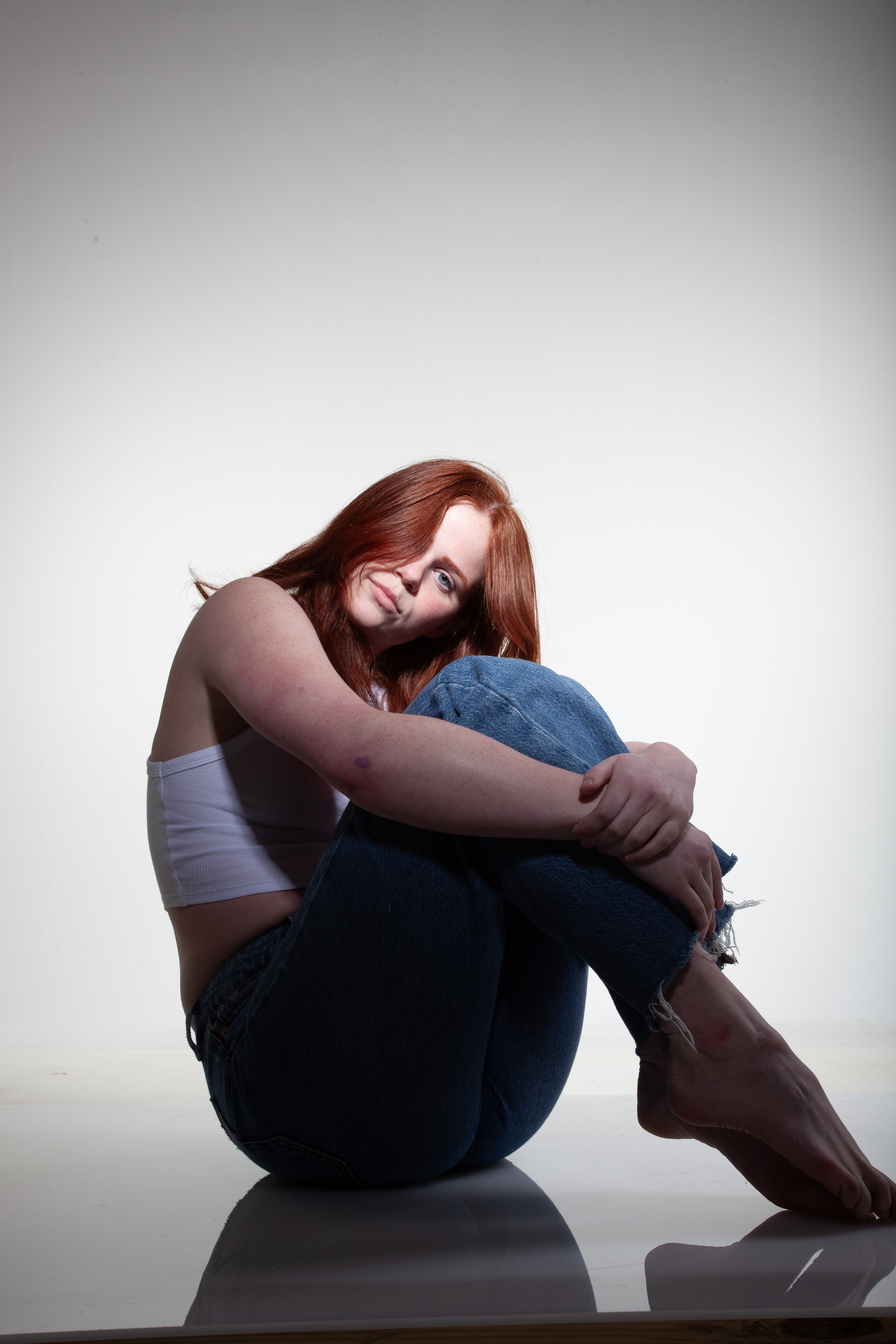 Red headed model sitting on a white floor with dramatic lighting