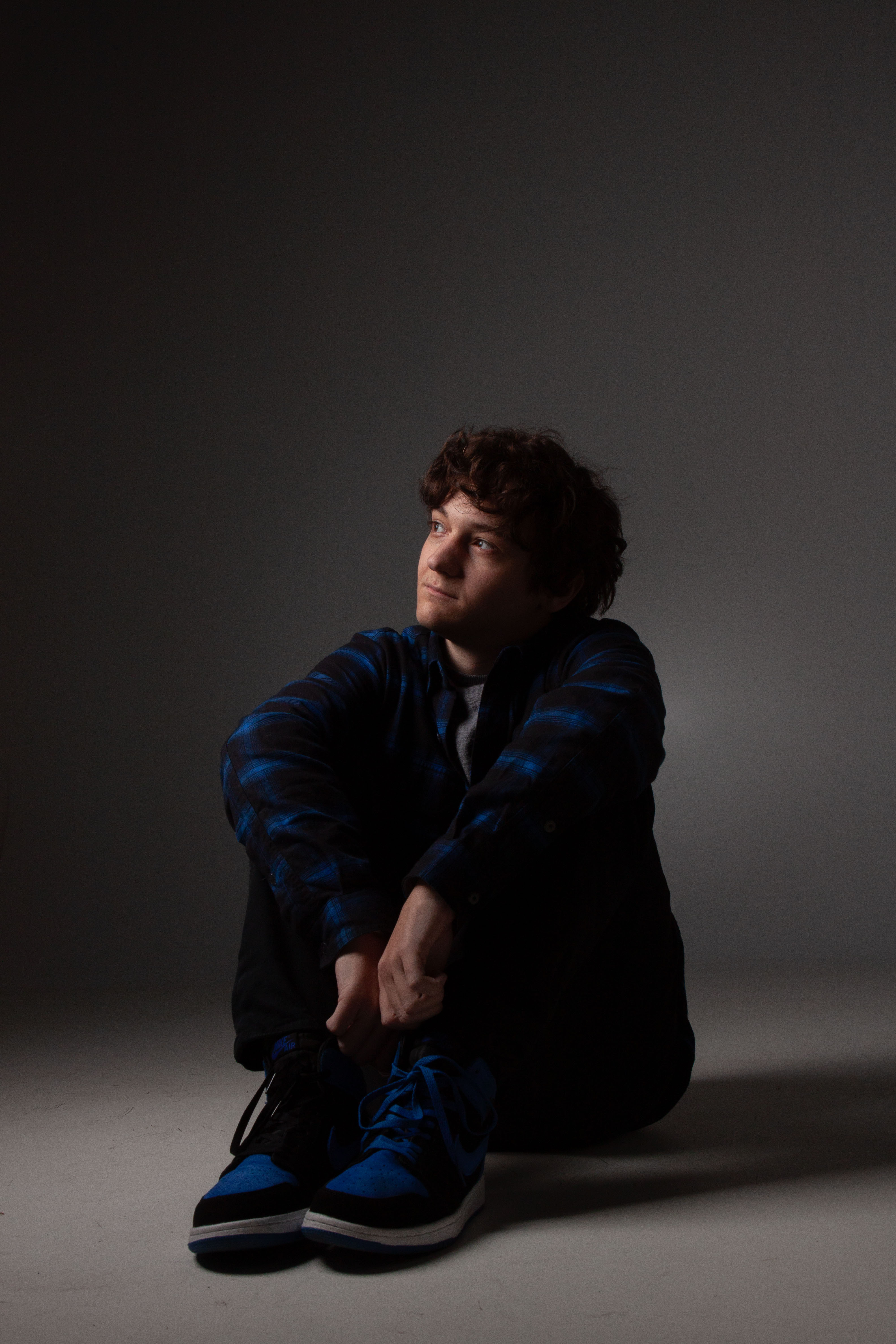 Model sitting on a while floor with dramatic lighting