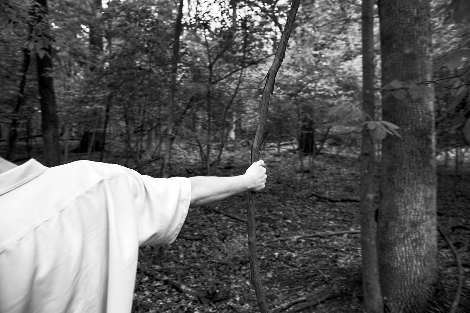 Black and white image of a hand and arm wrapping around a tree branch